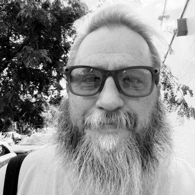 Jason, founder of New To Olde Kensington, a bearded man in glasses on a city sidewalk